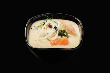 Thai soup with seafood, salmon, tiger shrimp, mussels, hondashi, shiitake mushrooms, togarashi pepper, leeks, sesame seeds. Thai cuisine. Isolated on black background