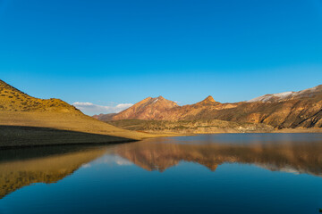 Beautiful panoramic view on the blues clear sky, lake and mountais, reflection in the water.