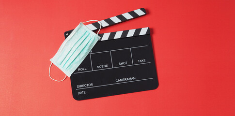 Fototapeta na wymiar Black clapper board or movie slate and face mask on red background.It is use in video production or movie and cinema industry.