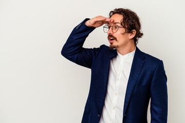 Young business man isolated on white background looking far away keeping hand on forehead.