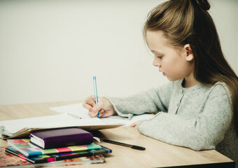 teen girl writing at the table on a white background