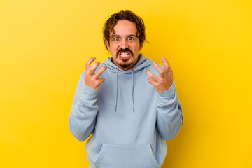 Young caucasian man isolated on yellow background upset screaming with tense hands.