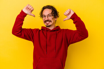 Young caucasian man isolated on yellow background feels proud and self confident, example to follow.