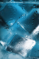 Ice cubes in a glass with crystal clear water on a blue background. Soft Selective Focus