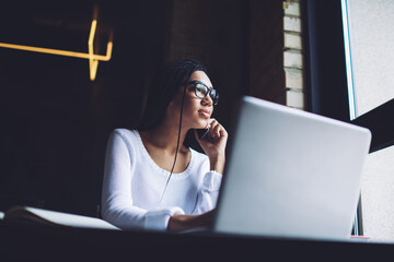 Pensive woman talking on smartphone in workspace