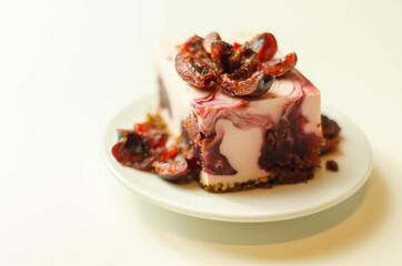 Japanese cheesecake with cherry sauce and fresh cherries on the ceramic plate and red background