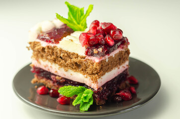 Colorful multi-layered cream chocolate cake with cherry jam and pomegranate