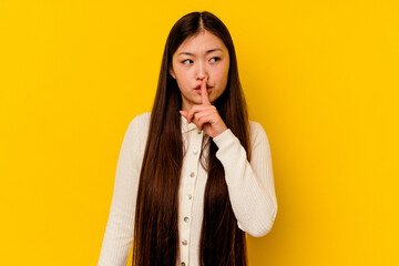 Young chinese woman isolated on yellow background keeping a secret or asking for silence. © Asier