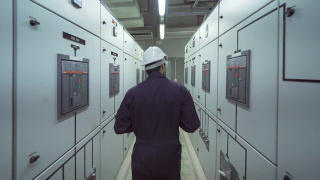 An engineer man or worker, people working in electrical room. Power energy motor machinery cabinets in control or server room, operator station network and circuit center in industry factory system.