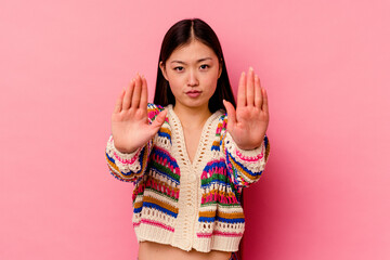 Young chinese woman isolated on pink background standing with outstretched hand showing stop sign, preventing you.