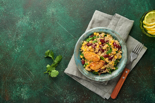 Mexican black bean corn quinoa salad with caramelized lemon in old vintage clay bowl on a dark green concrete background. Traditional Mexican cuisine dish. Top view, mock up.