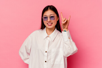 Young chinese woman isolated on pink background showing rock gesture with fingers