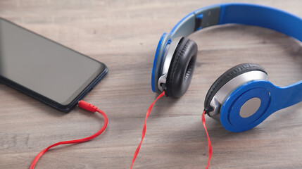 Blue headphones and smartphone on the wooden table.