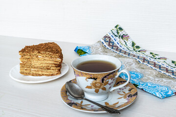 Gold cup of tea in focus. A slice of honey cake.