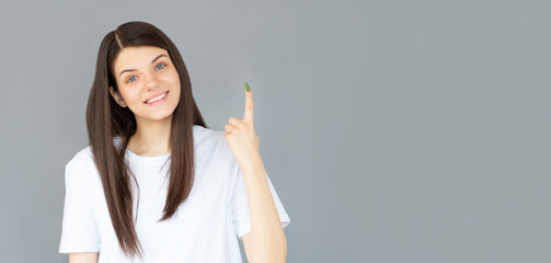 Attractive woman pointing up isolated on gray background