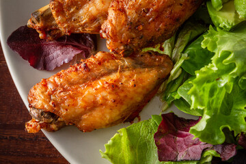 macro top view of a plate with roasted chicken wings and salad