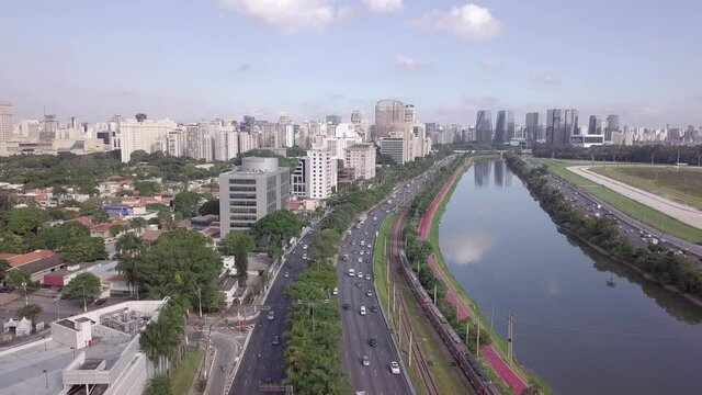 Drone aerial view of Marginal Pinheiros Avenue landscape, river, car traffic, buildings cityscape and Sao Paulo city skyline.	 Brazil. Concept of urban, metropolis, corporate, pollution, transport. 4K