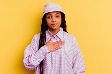 Young african american woman isolated on yellow background taking an oath, putting hand on chest.