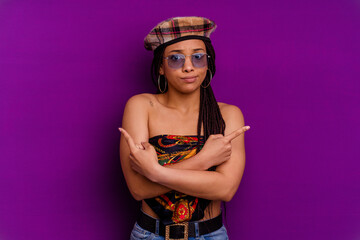 Young african american woman isolated on yellow background Young african american woman isolated on yellow background points sideways, is trying to choose between two options.