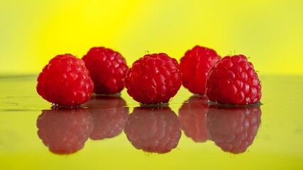 Ripe red raspberries on a mirror wet surface