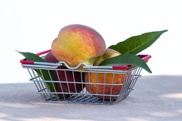Ripe peaches and green leaves in a metal basket