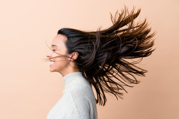 Young indian woman moving her hair isolated on beige background