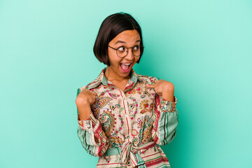 Young mixed race woman isolated on blue background surprised pointing with finger, smiling broadly.