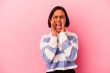 Young mixed race woman isolated on pink background shouting excited to front.