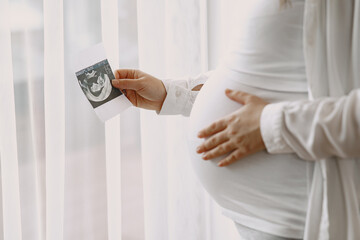 Pregnant woman stands by the window and looks at photo © hetmanstock2