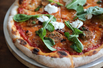 Italian Sausage and rocket salad pizza on wood background