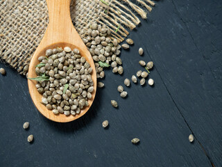 Hemp seeds in a wooden spoon on a black wooden table