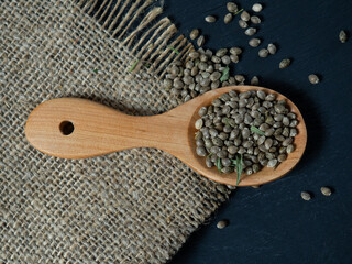 Hemp seeds in a wooden spoon on a black wooden table