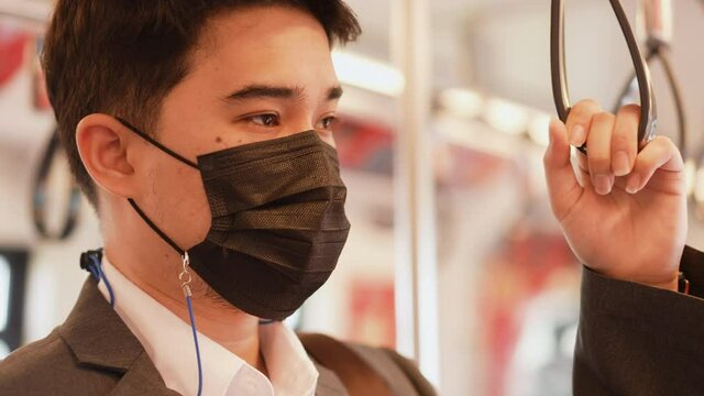 slow motion scene of middles eastern businessman hand holding handstrap handle in the public transport to go to work in the rush time (morning) for new normal lifestyle and transportation concept