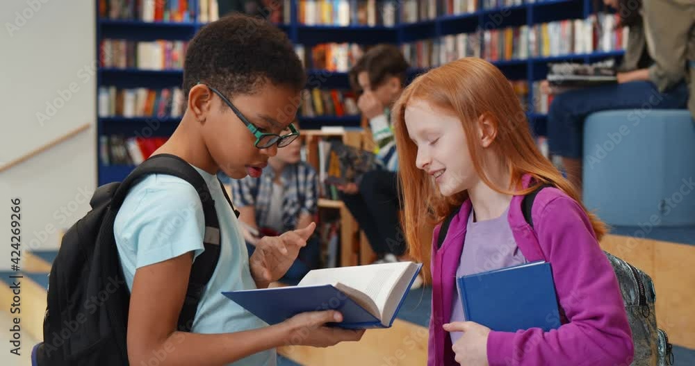 Poster multiethnic schoolchildren reading book and talking in library