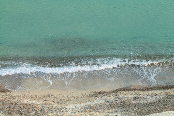 View of the sand, pebbles and clear sea from above. Marine background.