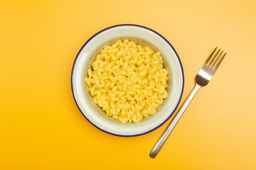 Pasta background. Mac and Cheese pasta on a yellow background. American style Italian pasta with cheese.