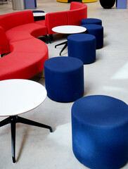 Curved red sofas and blue stools