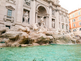 Fototapeta na wymiar Trevi Fountain flowing azure water close view. Aqueduct-fed marble rococo fountain, by Nicola Salvi. Travel sights of Italy