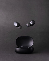 Auriculares bluetooth volando en estudio fondo negro
