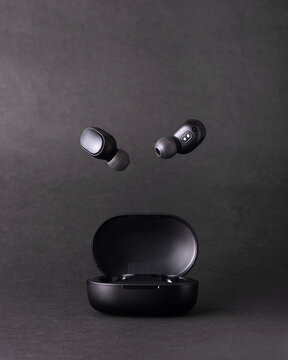 Auriculares bluetooth volando en estudio fondo negro