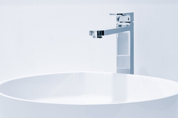 Luxury faucet mixer and white towel on a white sink in a beautiful gray bathroom. Sanitary...