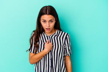 Young Indian woman isolated on blue background surprised pointing with finger, smiling broadly.