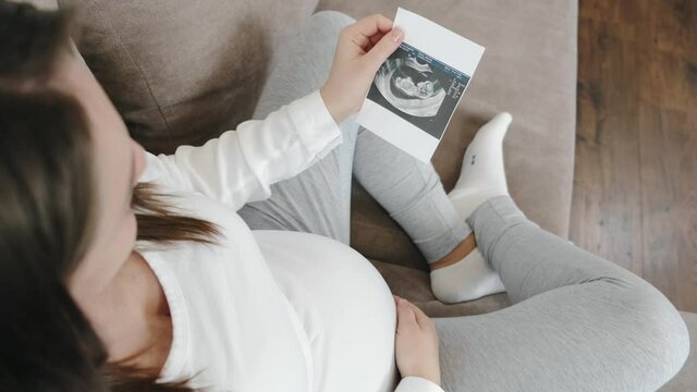 Portrait of cheerful pregnant girl showing ultrasound scan image