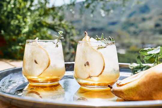 Fresh and healthy cocktail or mocktail with pear, ice and herbs on the steel tray. Refreshing drink in the garden.