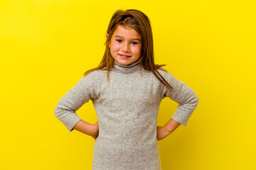 Little caucasian girl isolated on yellow background confident keeping hands on hips.