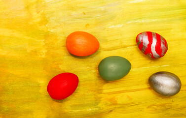 Red, orange, green, metallic eggs on an orange textured background. Five decorative handmade eggs...