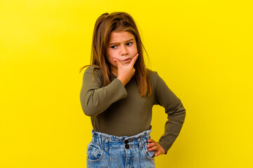 Little caucasian girl isolated on yellow background contemplating, planning a strategy, thinking...