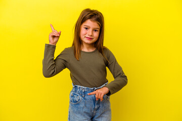 Little caucasian girl isolated on yellow background pointing to different copy spaces, choosing one...