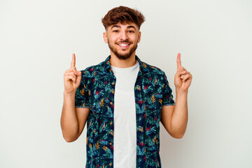 Young Moroccan man isolated on white background indicates with both fore fingers up showing a blank...