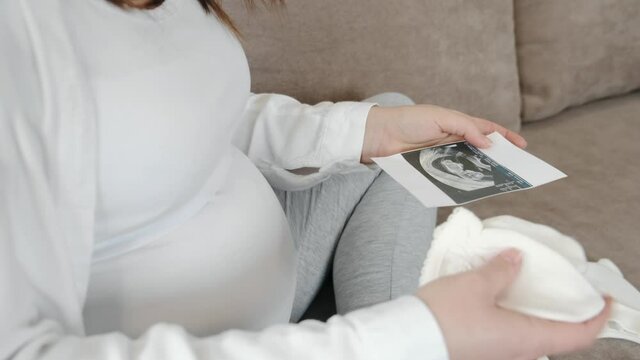 Portrait of cheerful pregnant girl showing ultrasound scan image